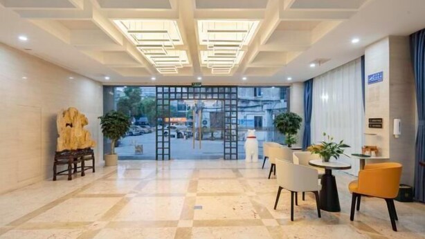 A hotel lobby with a checkered floor, a reception desk, and a view of the street through a glass door. - Kaiyue Business Hotel（Ninefang City Shop,Northmen Road ） (KUNSHAN)