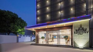 A modern hotel entrance with a glass facade, a wooden slatted wall, and a well-lit reception area. - Kaiyue Business Hotel（Ninefang City Shop,Northmen Road ） (KUNSHAN)