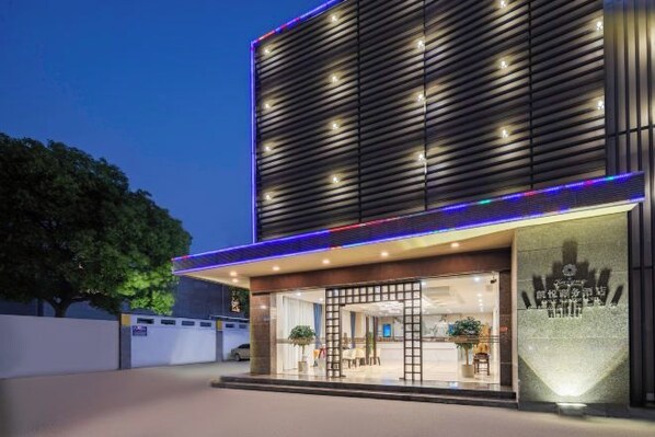 A modern hotel entrance with a glass facade, a wooden slatted wall, and a well-lit reception area. - Kaiyue Business Hotel(Ninefang City Shop,Northmen Road ) (KUNSHAN)