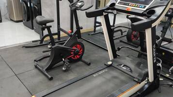 A gym with exercise equipment including a treadmill, stationary bike, and elliptical machine.