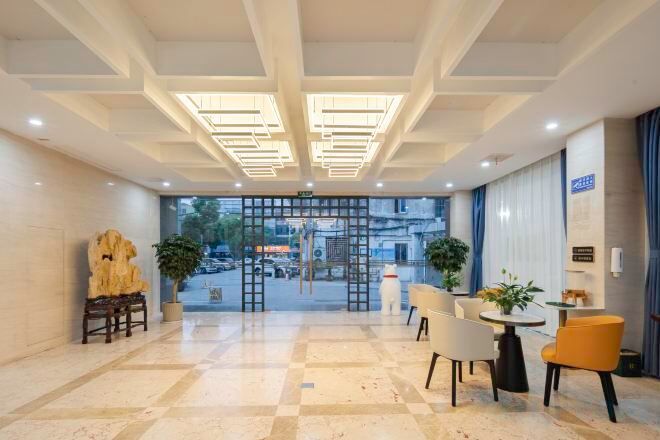 A hotel lobby with a checkered floor, seating area, and a view of the street through a glass door.