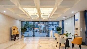 A hotel lobby with a checkered floor, seating area, and a view of the street through a glass door.