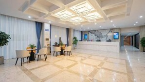 A hotel lobby with a reception desk, a seating area with tables and chairs, and a decorative ceiling. - Kaiyue Business Hotel（Ninefang City Shop,Northmen Road ） (KUNSHAN)