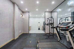 A modern gym with treadmills, a weight machine, and a mirrored wall. - Kaiyue Business Hotel(Ninefang City Shop,Northmen Road ) (KUNSHAN)