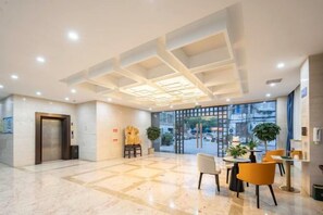 A hotel lobby with a reception desk, seating area, and a glass door entrance. - Kaiyue Business Hotel（Ninefang City Shop,Northmen Road ） (KUNSHAN)