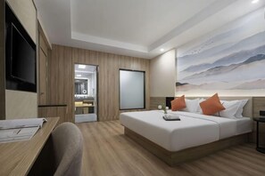 Une chambre d’hôtel moderne avec un lit, un bureau et un tableau au mur.
