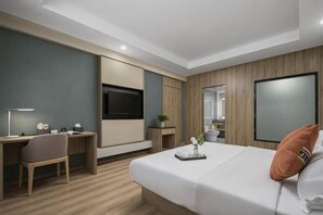 Une chambre d’hôtel moderne équipée d’un lit, d’un bureau, d’une télévision et d’un miroir.