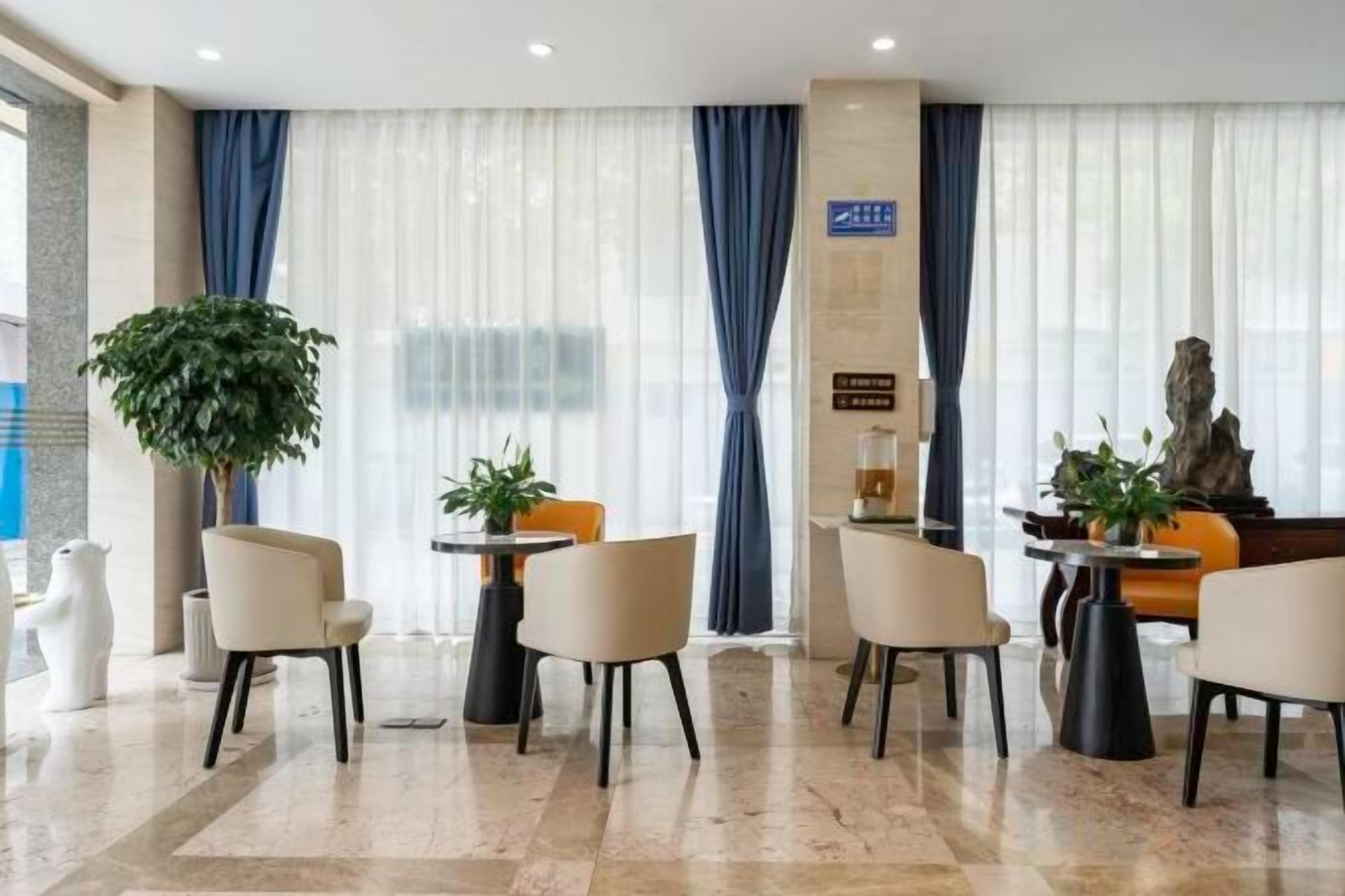 Een hotel lobby met een receptiebalie, een zithoek en een grote plant.