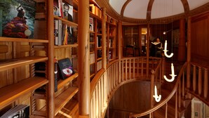 A library with wooden bookshelves, a spiral staircase, and a large circular skylight. - Clarance Hotel Lille (Lille)