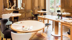 A restaurant interior with wooden paneling, round tables, and hanging light fixtures. - Clarance Hotel Lille (Lille)