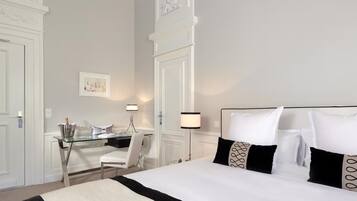 Une chambre d’hôtel avec un grand lit, un bureau avec une chaise et deux lampes de chevet.