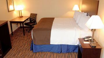 A hotel room with a bed, a desk, a chair, and two lamps.
