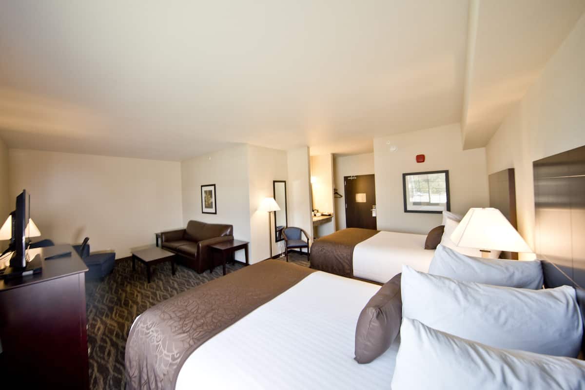 Une chambre d’hôtel avec deux lits, un bureau, une chaise et un téléviseur.