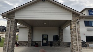 A building with a covered entrance, stone pillars, and a sign for 'Cobb's Inn & Suites'. - Cobblestone Inn & Suites - Denison - Oak Ridge (Denison)