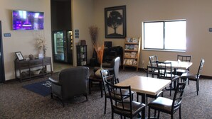 A hotel lobby with a reception desk, seating area, and a large window providing natural light. - Cobblestone Inn & Suites - Denison - Oak Ridge (Denison)