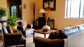 A living room with a sofa, armchairs, a coffee table, a lamp, and a vase with decorative sticks. - Cobblestone Inn & Suites - Denison - Oak Ridge (Denison)