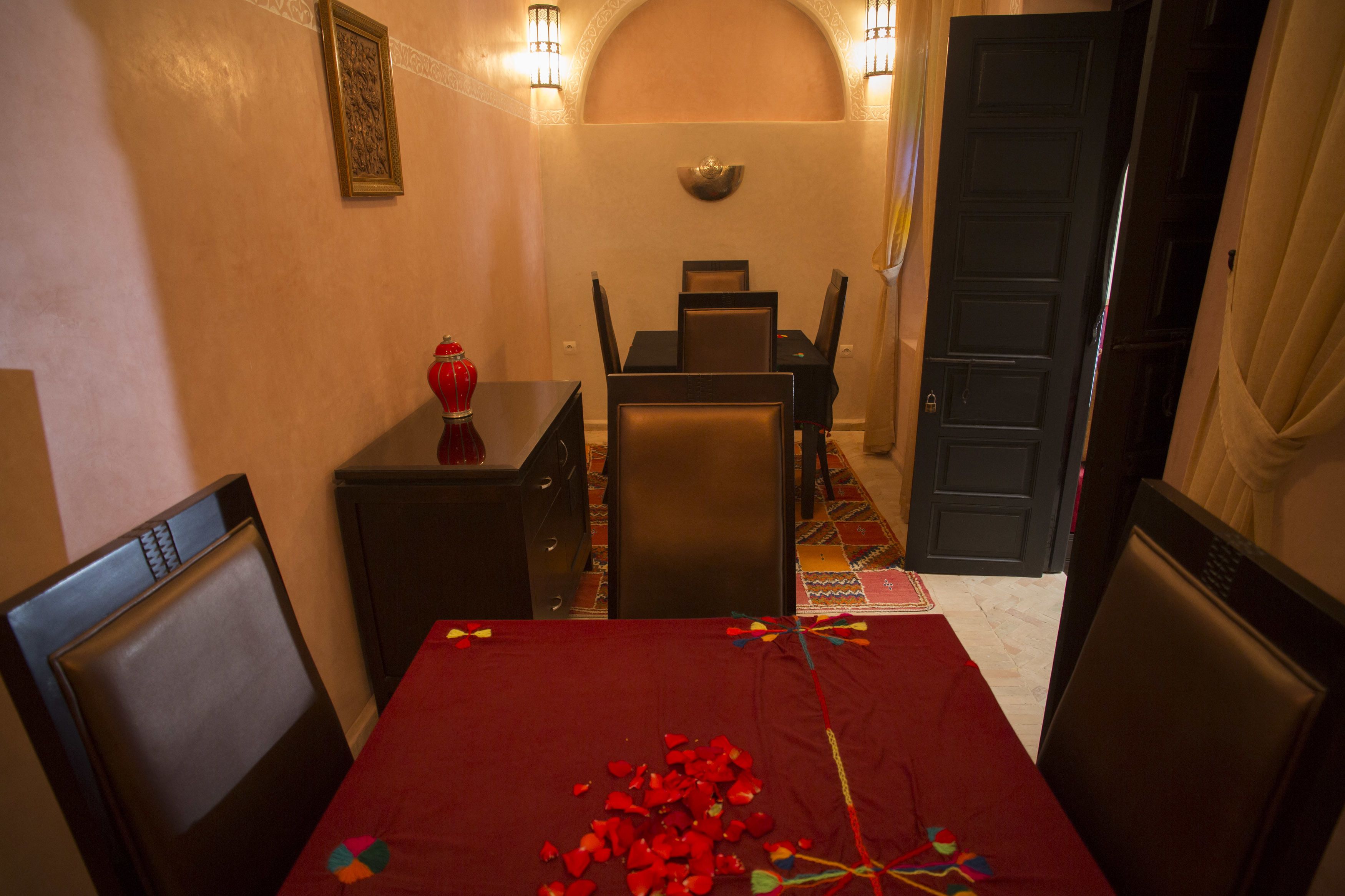 Un comedor con una mesa preparada para cuatro, un mueble pequeño y una puerta que da a otra habitación.