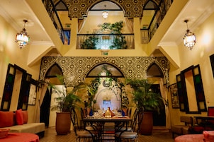 A dining area with a high ceiling, ornate arches, and potted plants.
