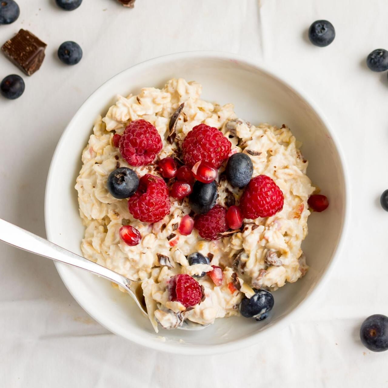 A bowl of oatmeal with raspberries and blueberries.