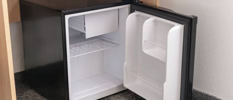 Uma geladeira compacta com exterior preto, interior branco e uma prateleira.