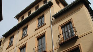 A multi-story building with balconies, a sign for 'cuadros Baix', and another for 'Medieval Granada'. - Apartamentos Casa de la Lonja (Granada)