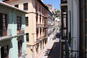 A narrow street lined with multi-story buildings, each with balconies and parked scooters. - Apartamentos Casa de la Lonja (Granada)