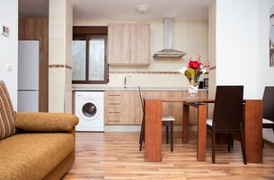 Un espacio habitable compacto con sofá, mesa de comedor, sillas, lavadora y armarios de madera.