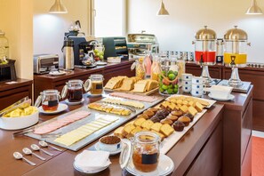 A breakfast buffet with various food items, coffee machines, and a juice dispenser. - Hotel LP Equipetrol (Santa Cruz)