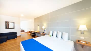 Una habitación de hotel con cama, escritorio, silla, sofá y lámpara.