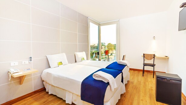 A hotel room with two beds, a desk, a chair, and a small table. - Hotel LP Equipetrol (Santa Cruz)