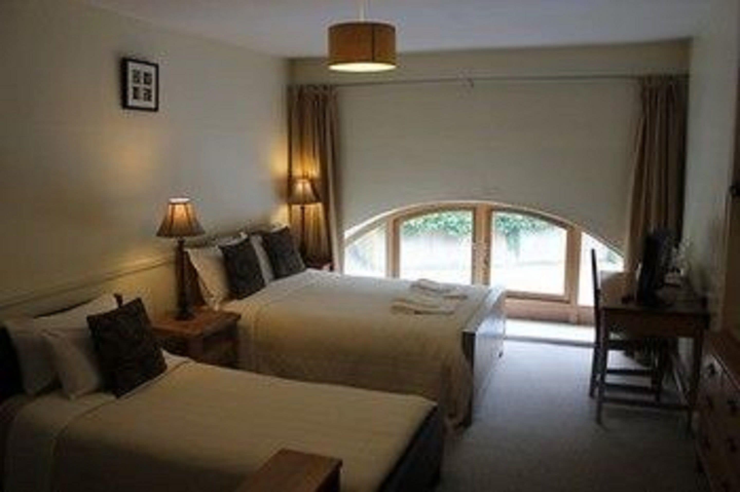 Ein Hotelzimmer mit zwei Betten, einem Schreibtisch und Blick ins Freie.