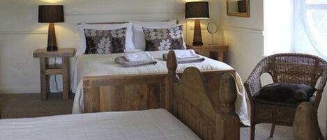 A bedroom with a wooden bed, two bedside tables with lamps, a wicker chair, and a mirror on the wall.