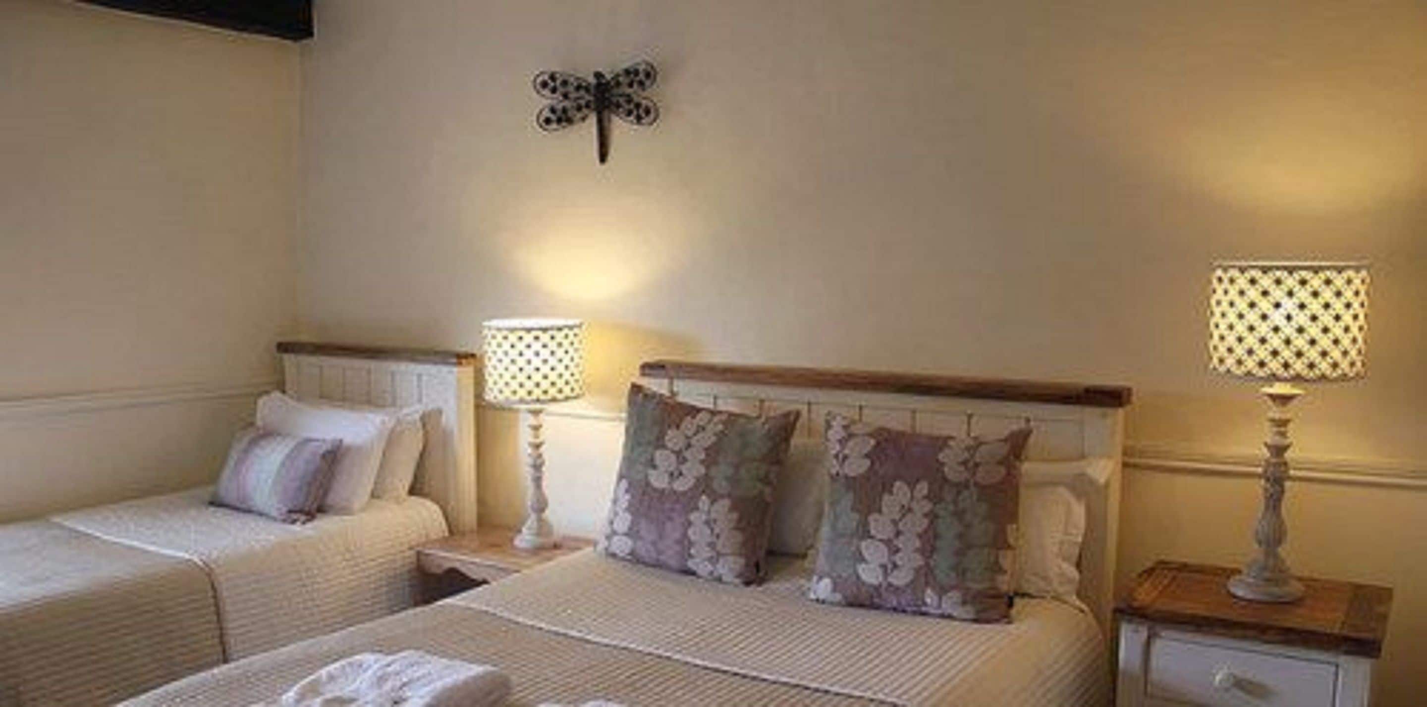 Une chambre d’hôtel avec deux lits, chacun muni d’une table de chevet et d’une lampe. Un papillon décoratif est accroché au mur.