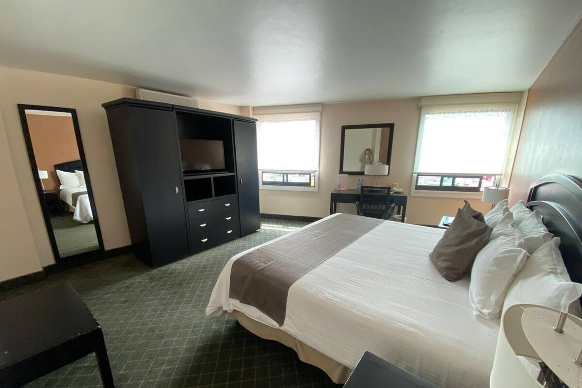 Una habitación de hotel con cama, escritorio, armario y espejo.
