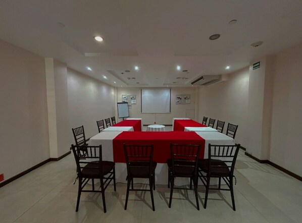 Une salle de conférence équipée d’une longue table, de chaises, d’un écran de projection et d’un tableau blanc.