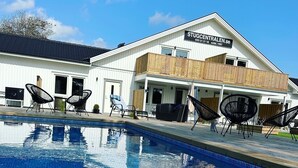 Una piscina con sillones de descanso y un edificio con la leyenda "STUGCENTRALEN.SE" al fondo.