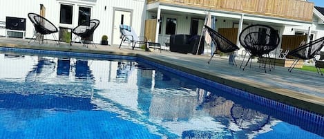 Una piscina con sillones de descanso y un edificio con la leyenda "STUGCENTRALEN.SE" al fondo.