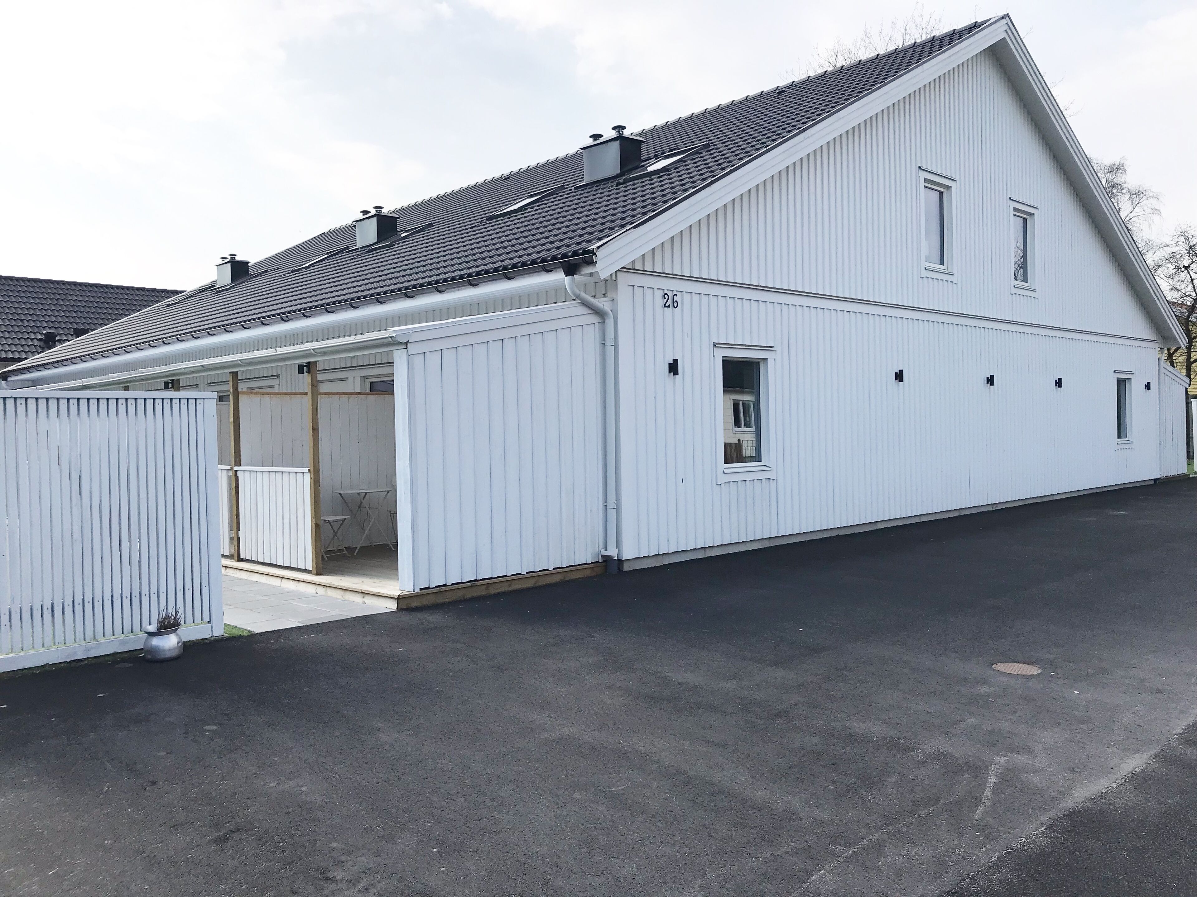 A white building with a sloped roof and a covered garage.