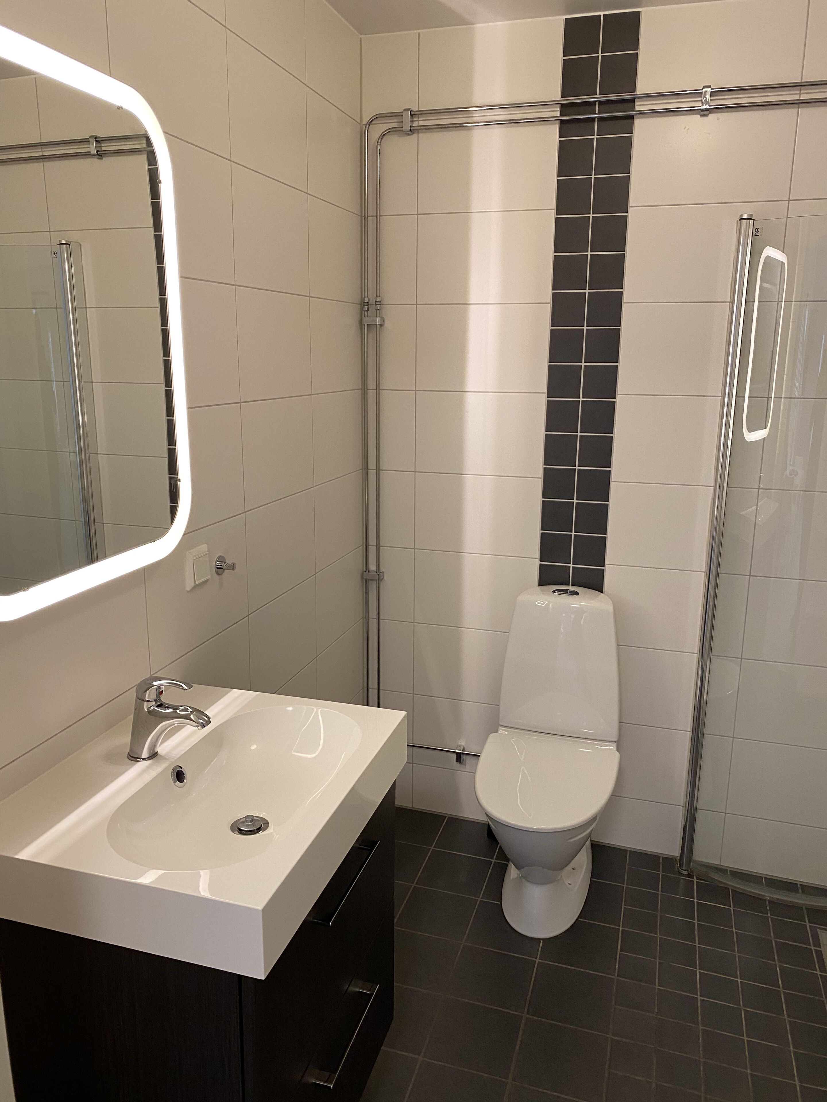 Un bagno moderno con lavandino bianco, servizi igienici e cabina doccia in vetro.
