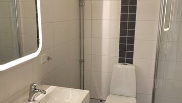 Un bagno moderno con lavandino bianco, servizi igienici e cabina doccia in vetro.