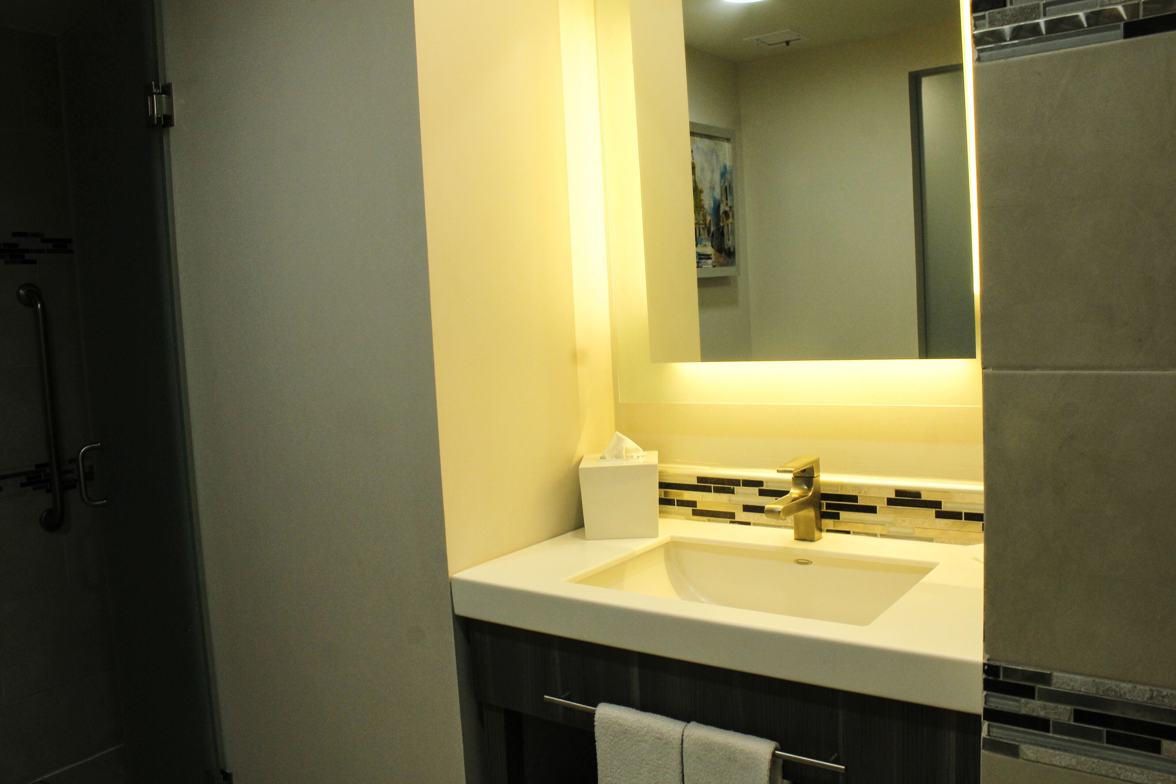 A bathroom with a white sink, a mirror, and a towel rack.