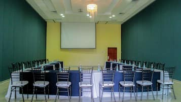 Ein Konferenzraum mit einer großen Leinwand, Reihen von Stühlen und Tischen für ein Meeting.