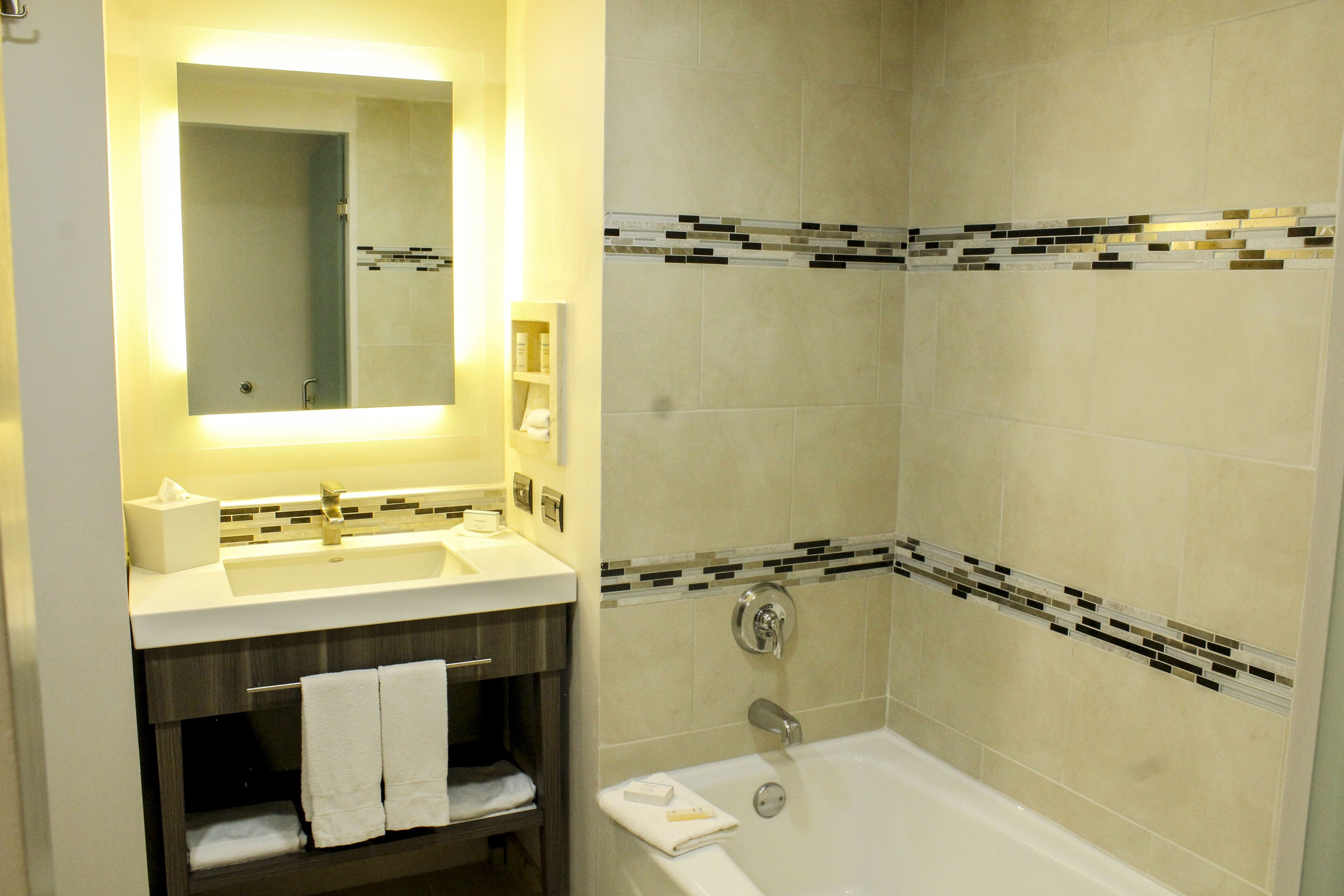 A bathroom with a sink, mirror, and bathtub.