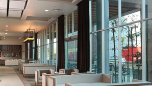 Eine moderne Hotelhalle mit Sitzbereichen, großen Fenstern und einer Rezeption.