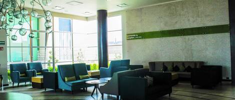 Um hall de entrada com diversas áreas de estar, incluindo sofás e cadeiras, uma mesa de centro e um balcão de recepção.