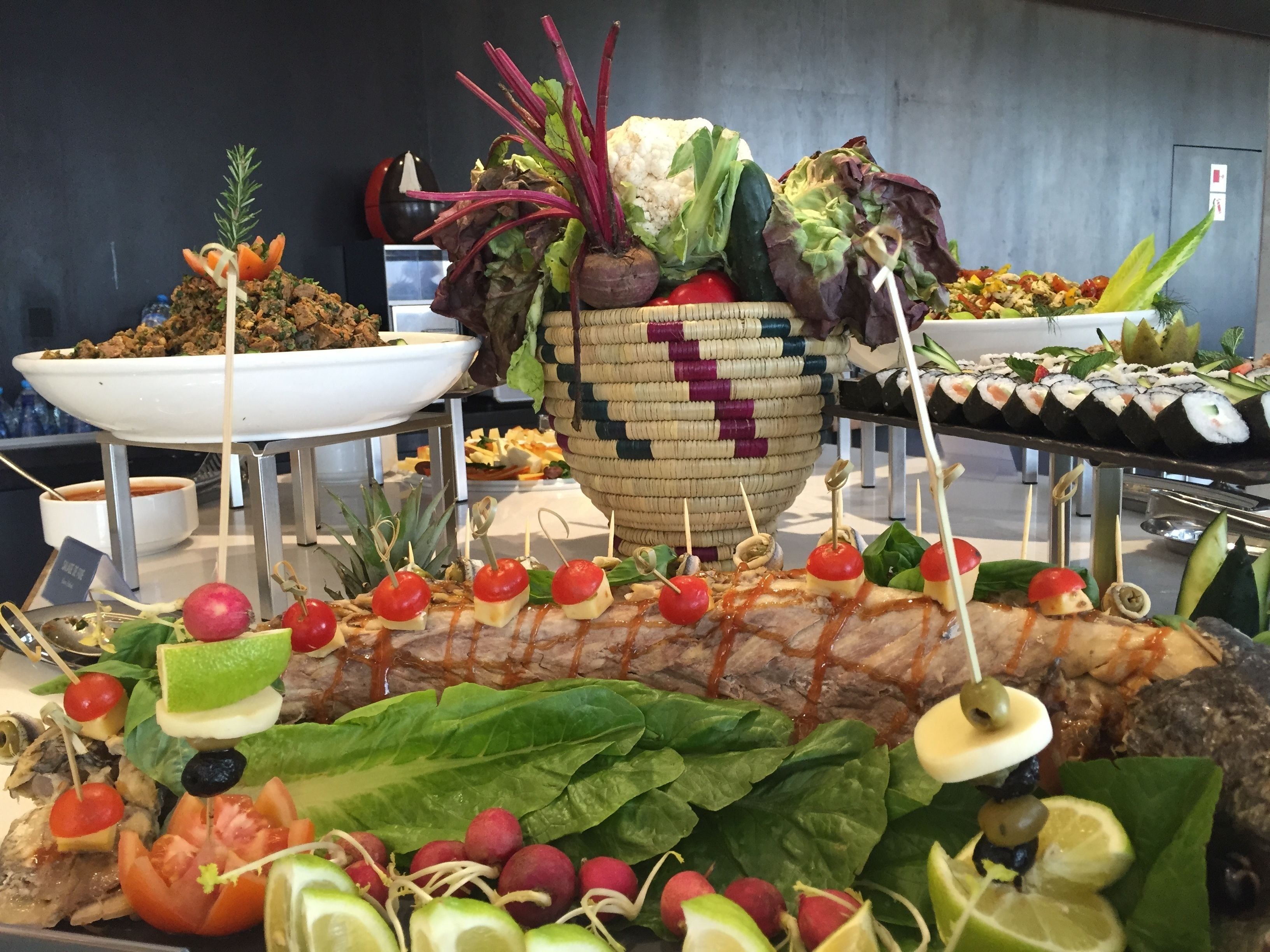 A buffet with various food items including skewers, salads, and a large fish centerpiece.