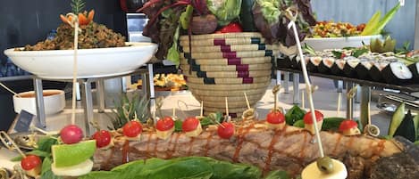 A buffet with various food items including skewers, salads, and a large fish centerpiece.