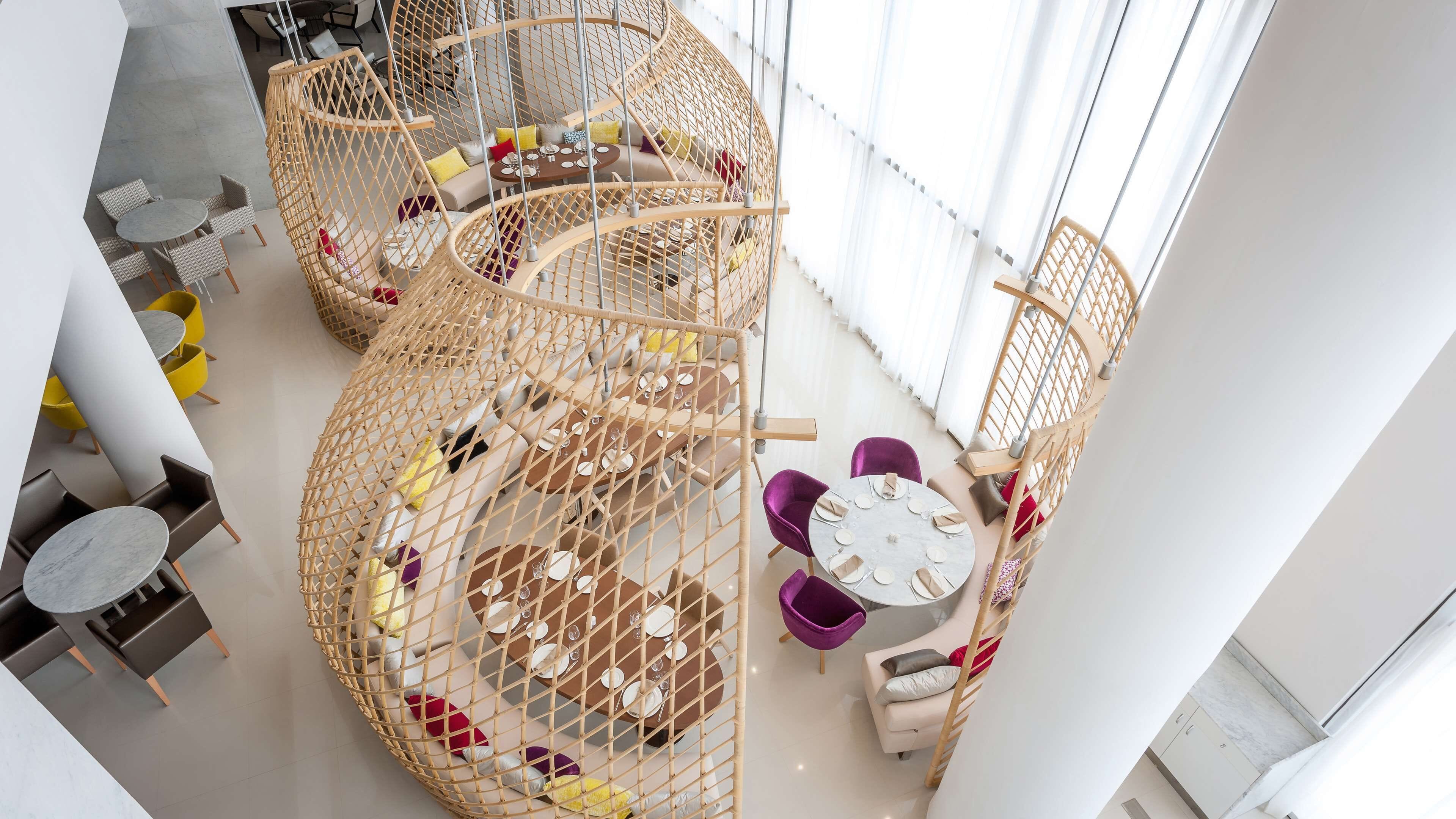 A modern interior with a spiral staircase, round tables, and chairs.
