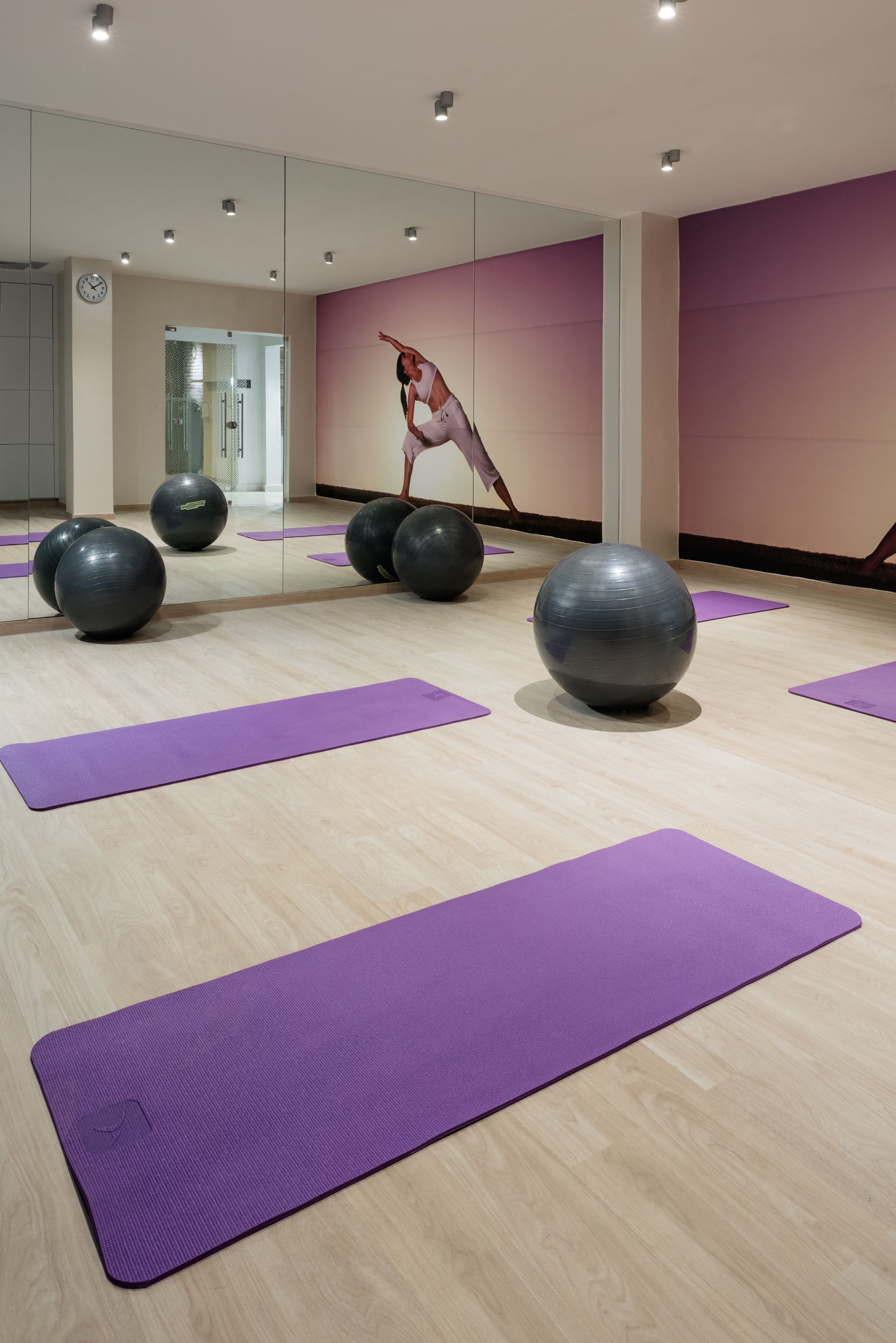 A fitness room with exercise balls and purple mats.