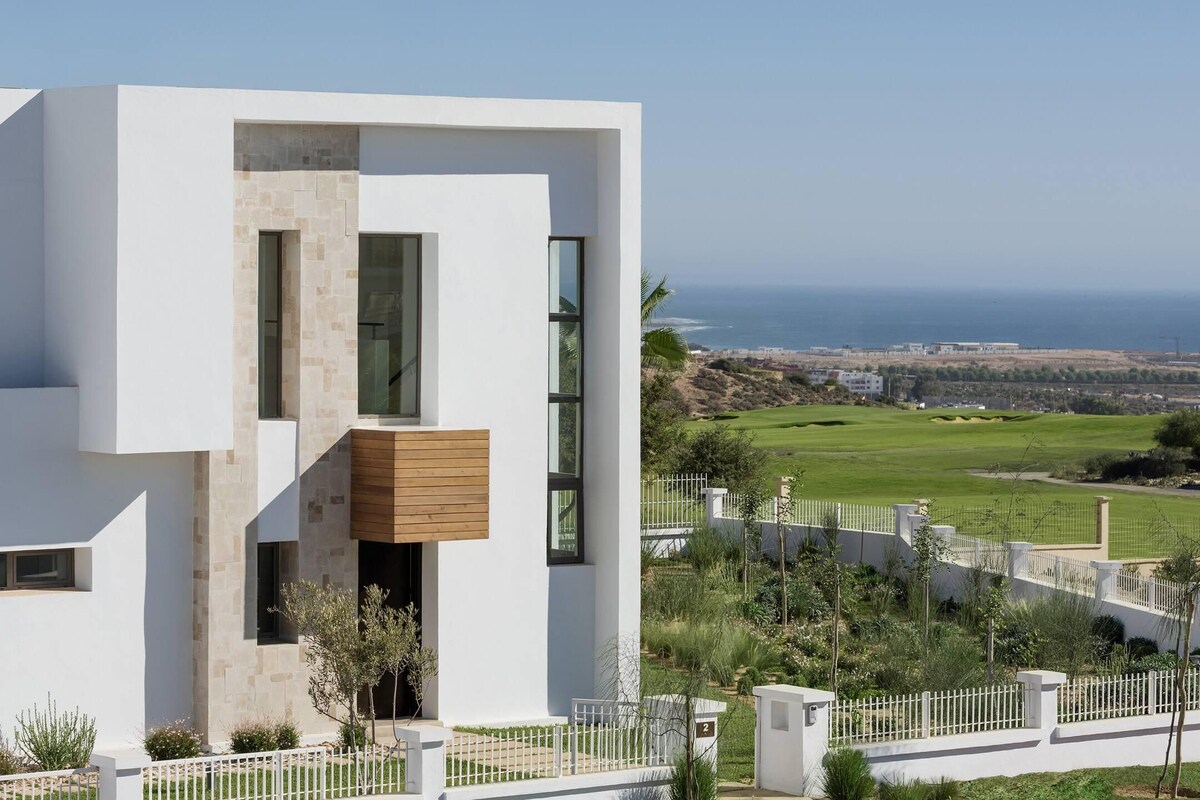 A modern building with a white facade, large windows, and a wooden balcony.
